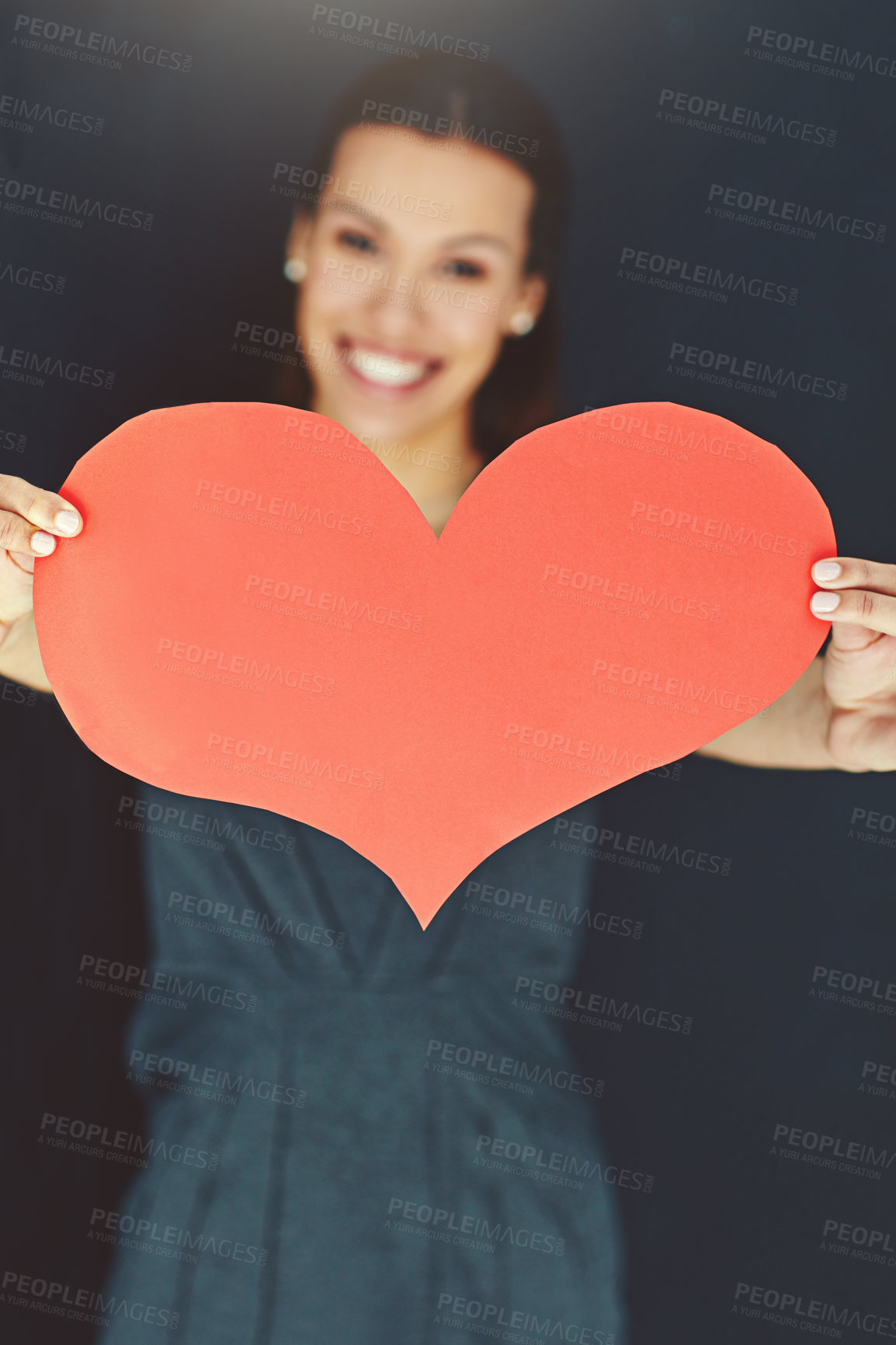 Buy stock photo Portrait of a young woman posing with a heart against a gray background