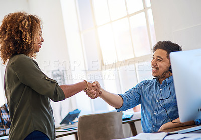Buy stock photo Shot of a young phone operator shaking hands with a coworker at his desk