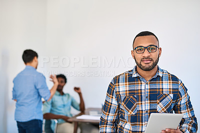 Buy stock photo Portrait of a young entrepreneur using a digital tablet at work with his team in the background