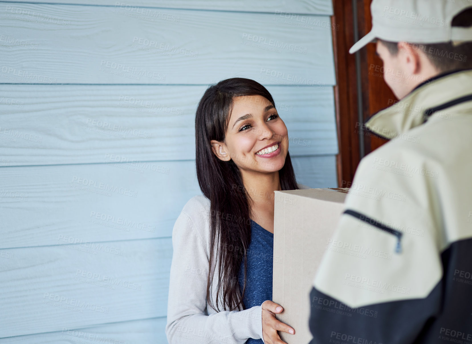 Buy stock photo Cropped shot of a young woman receiving her package from the courier