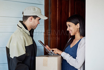 Buy stock photo Cropped shot of a young woman using a digital tablet to sign for her delivery from the courier