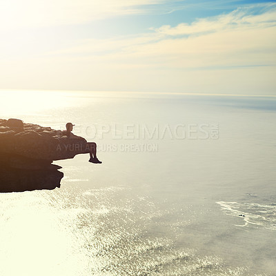 Buy stock photo Shot of an unidentifiable young man admiring an ocean view from a mountain overhang