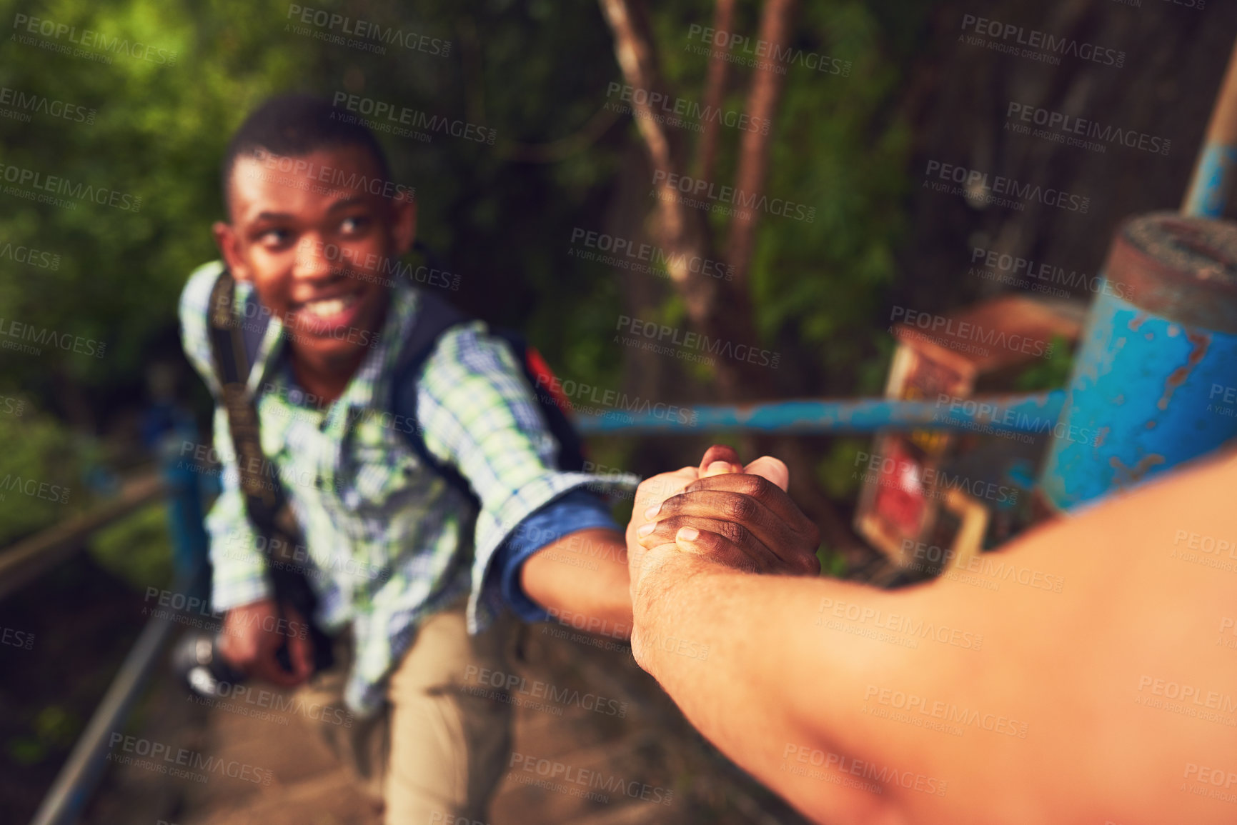 Buy stock photo Cropped shot of a young man helping a friend up a mountain trail