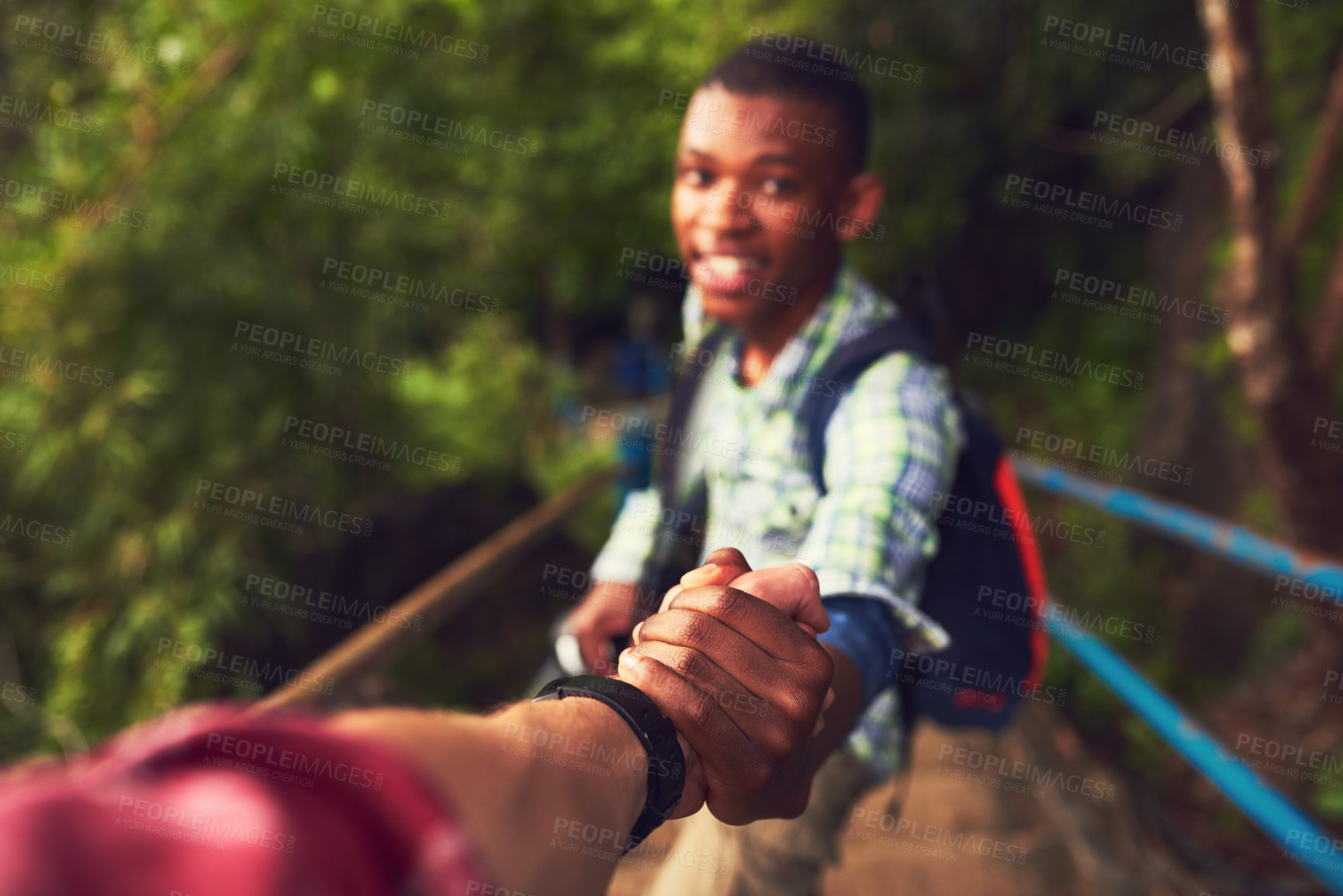 Buy stock photo POV shot of a young man helping a friend up a mountain trail