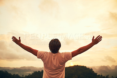 Buy stock photo Rear view shot of a young man standing outside with his arms outstretched