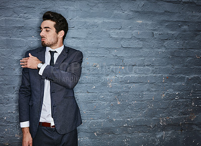 Buy stock photo Shot of a businessman brushing off his shoulders against a grey wall