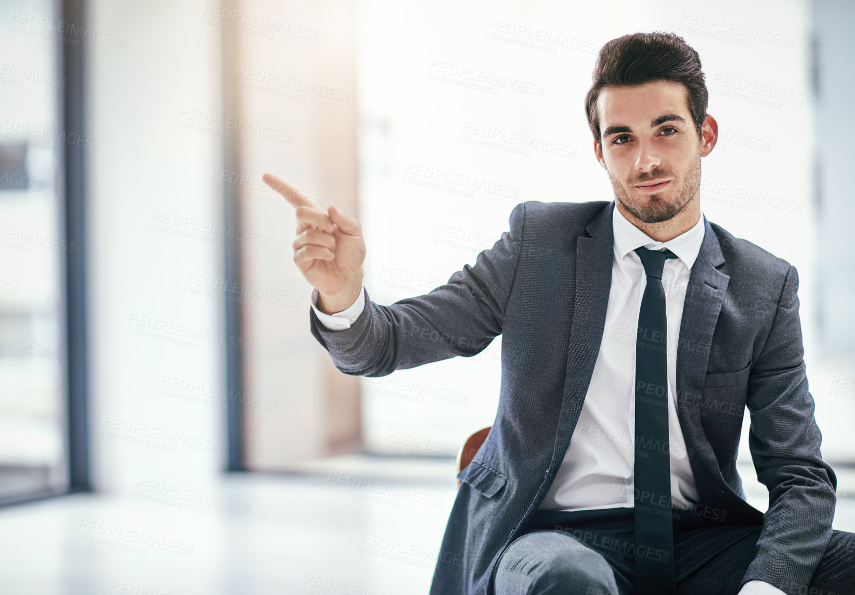 Buy stock photo Portrait of a trendy young businessman pointing to copyspace next to him in the office