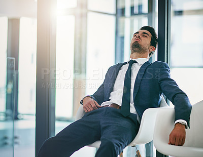Buy stock photo Shot of an exhausted young businessman resting on a chair in the office
