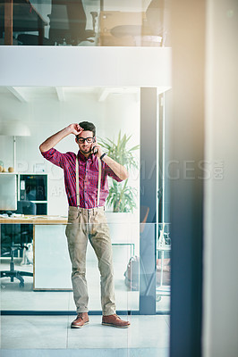 Buy stock photo Full length shot of a handsome young designer talking on his cellphone in the office