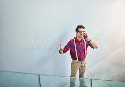 Buy stock photo High angle shot of a handsome young designer talking on his cellphone in the office