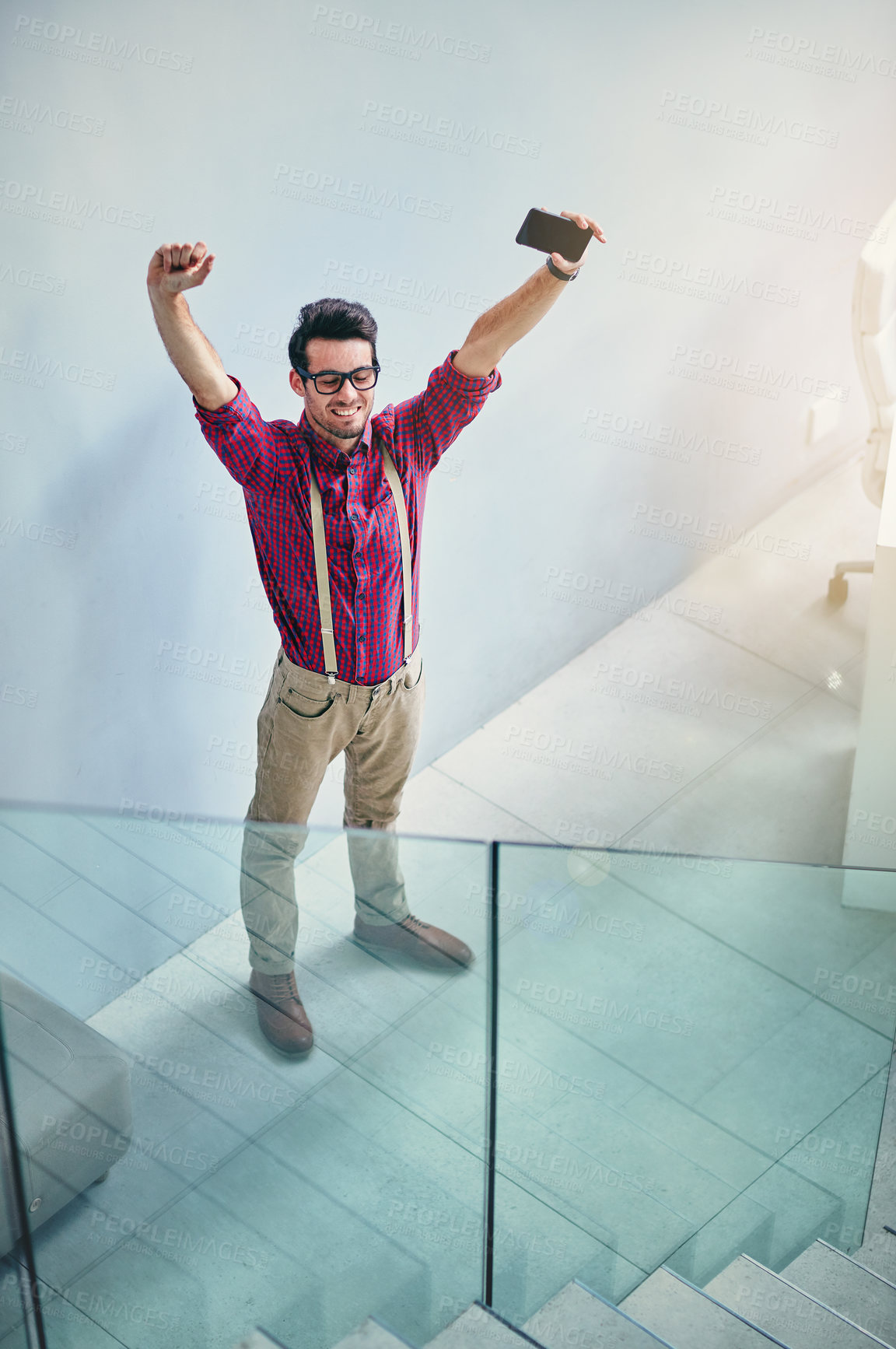 Buy stock photo High angle shot of a handsome young designer standing with his arms raised in the office