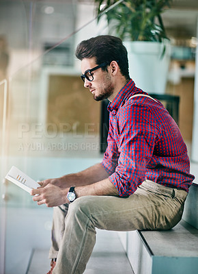 Buy stock photo Cropped shot of a handsome young designer looking at paperwork in his office