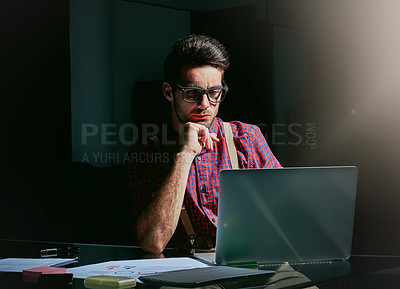 Buy stock photo Cropped shot of a handsome young designer working on his laptop in the office