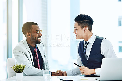 Buy stock photo Cropped shot of colleagues shaking hands while sitting in the office