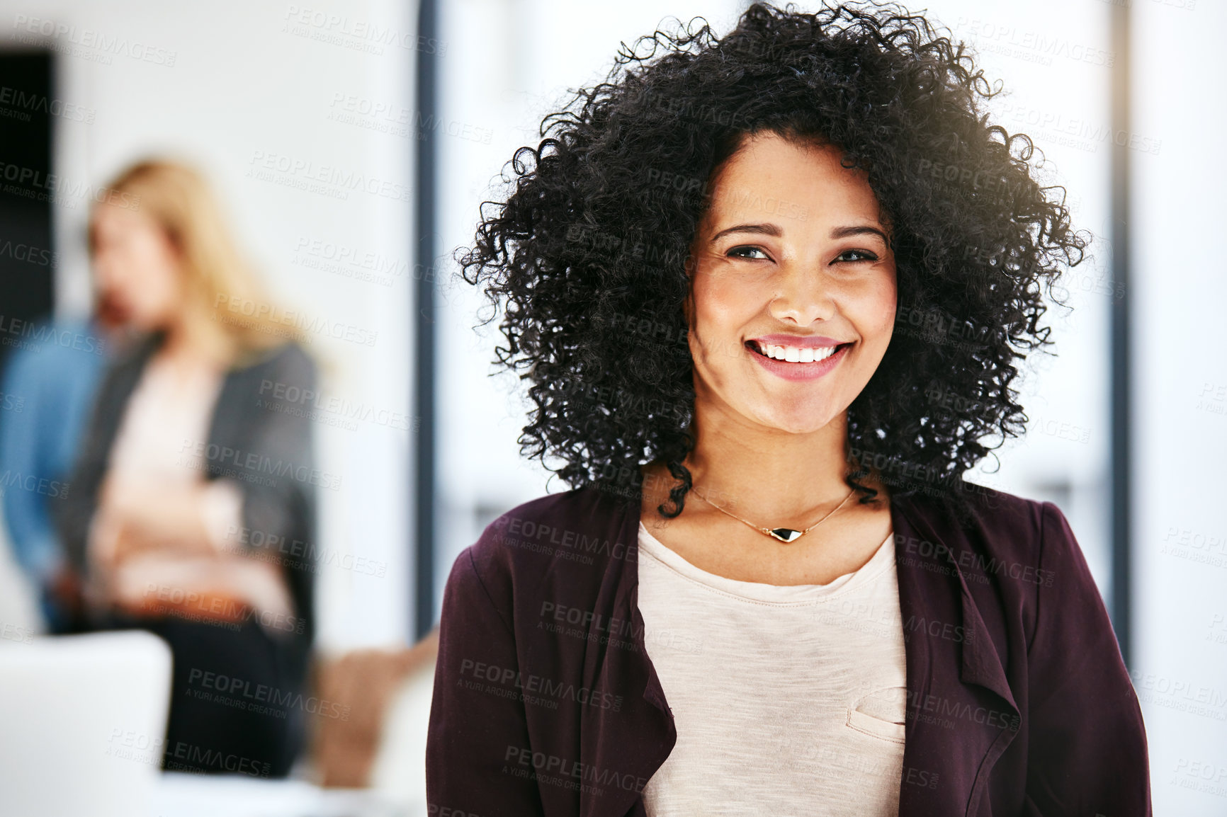 Buy stock photo Closeup portrait of a happy, successful and confident business woman standing in a office. Beautiful African American female smiling, with her colleagues in the blurred copyspace background.