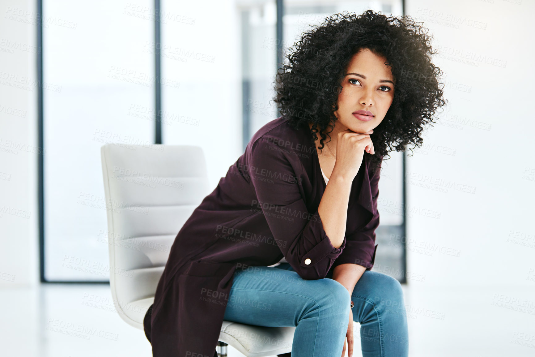 Buy stock photo Portrait of a confident young woman sitting on a chair at work in a modern office