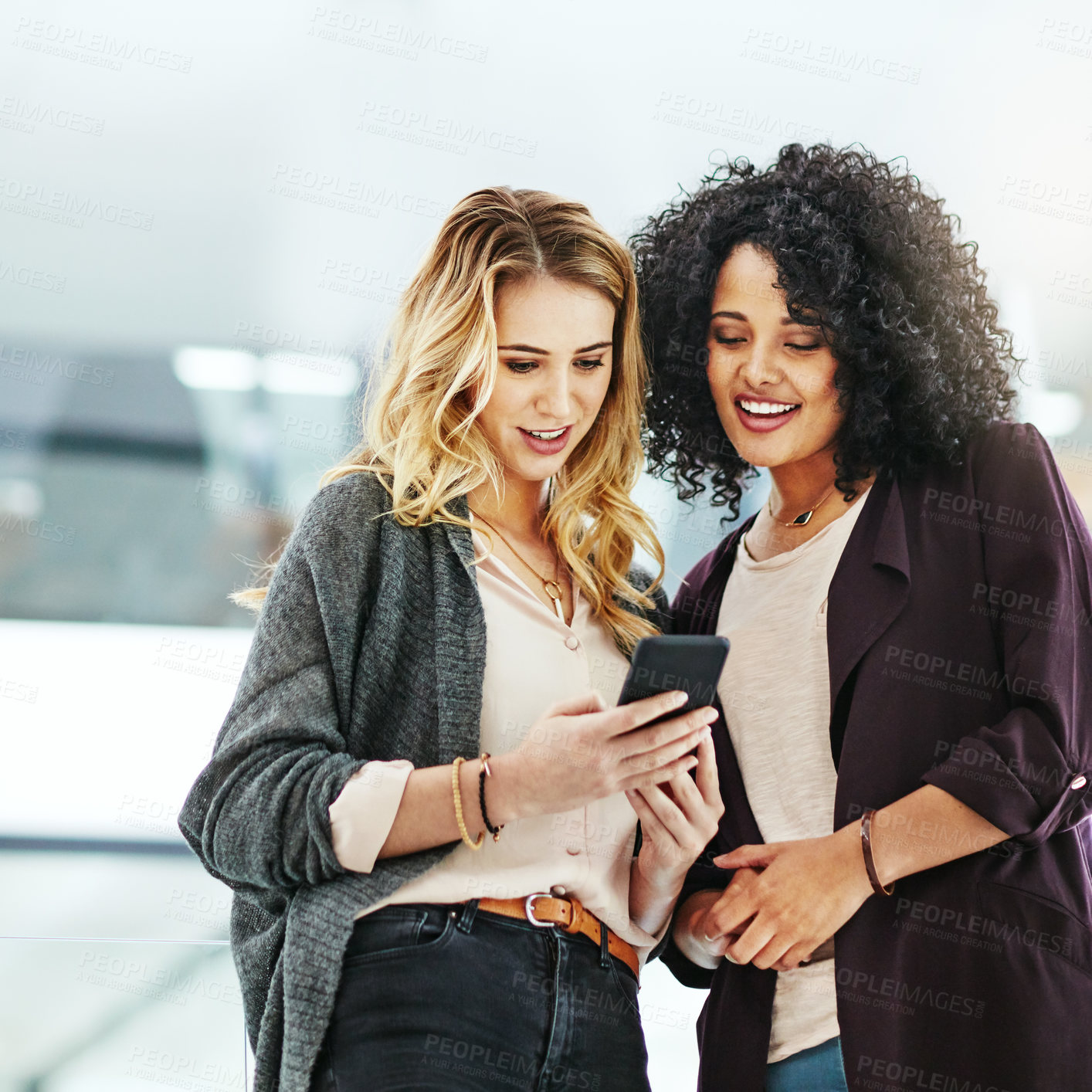Buy stock photo Business women browsing on a phone in their office at work. A female colleague showing her coworker a design, idea or plan on a cellphone at work. Working as a team, talking and planning for success