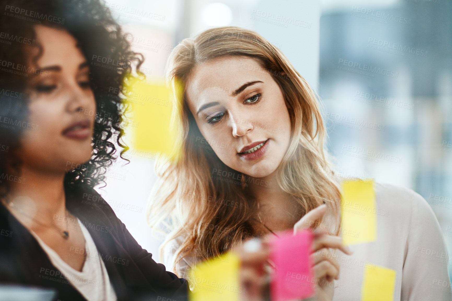 Buy stock photo Shot of two colleagues having a brainstorming session in a modern office