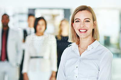 Buy stock photo Portrait of an ambitious young woman standing in a modern office with her colleagues in the background