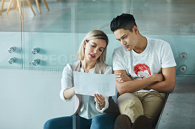 Buy stock photo Shot of two colleagues reading a document together at work