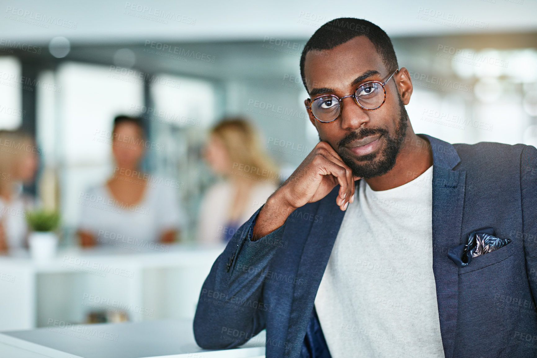 Buy stock photo Portrait of a confident black business man standing in a busy office. Proud, stylish and ambitious professional focused on his success and career while his employees have a meeting in the background