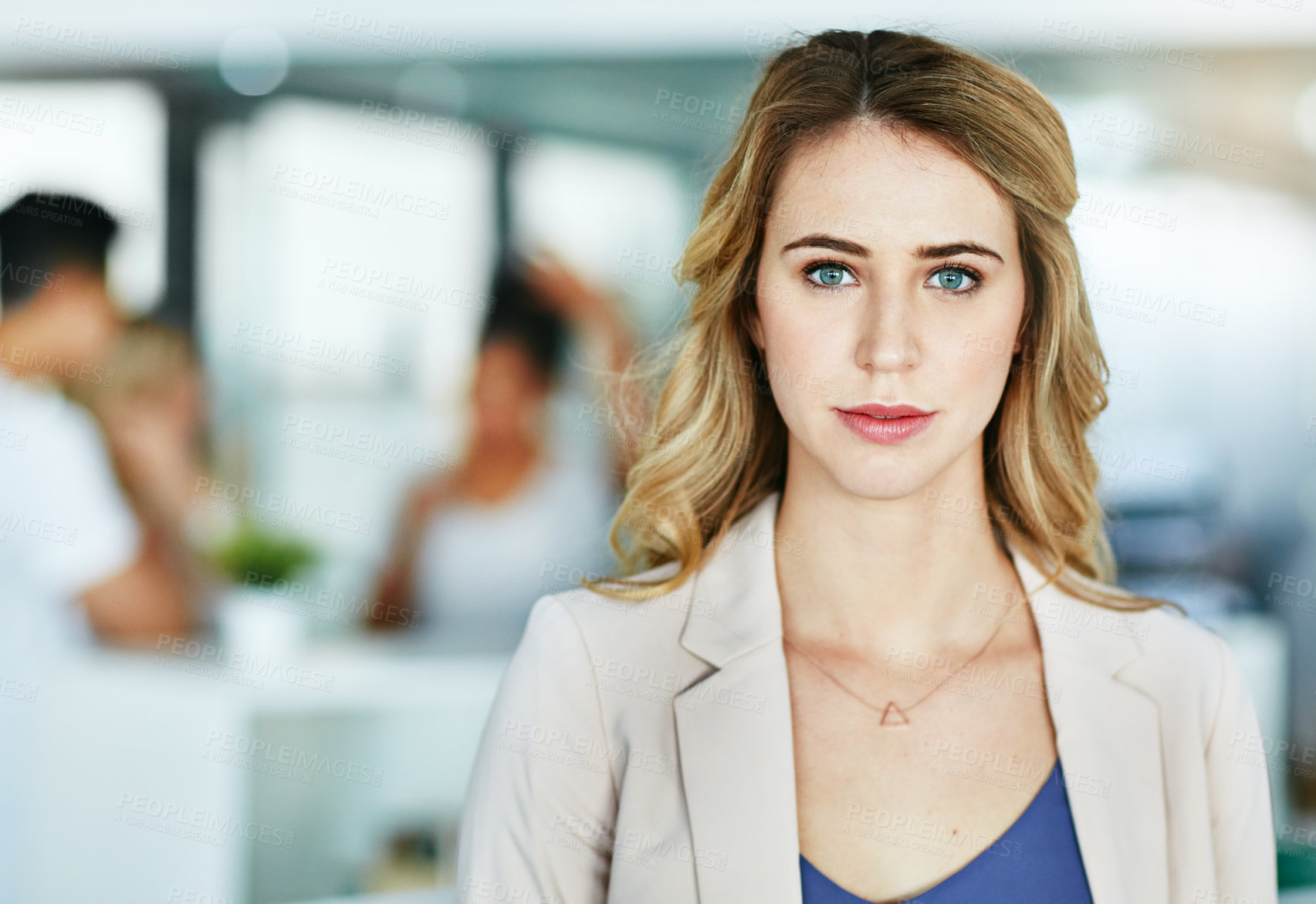 Buy stock photo Portrait of an ambitious young woman standing in a modern office with her colleagues in the background