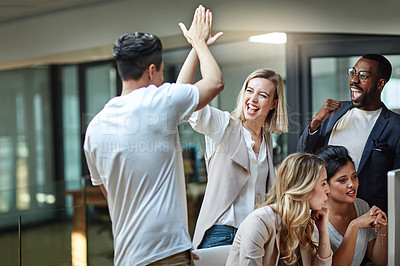 Buy stock photo Shot of a group of colleagues giving each other a high five while using a computer together at work