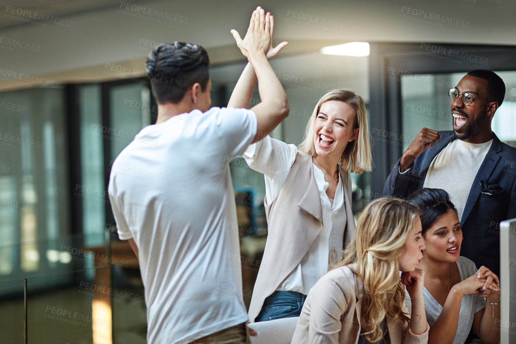 Buy stock photo Shot of a group of colleagues giving each other a high five while using a computer together at work