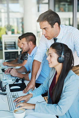 Buy stock photo Shot of a young man assisting his colleague in a call center