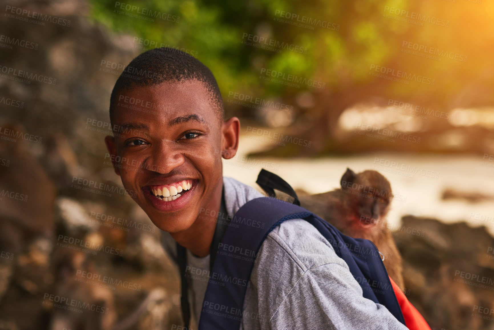 Buy stock photo Portrait of a happy young tourist exploring a tropical beach with a monkey on his backpack