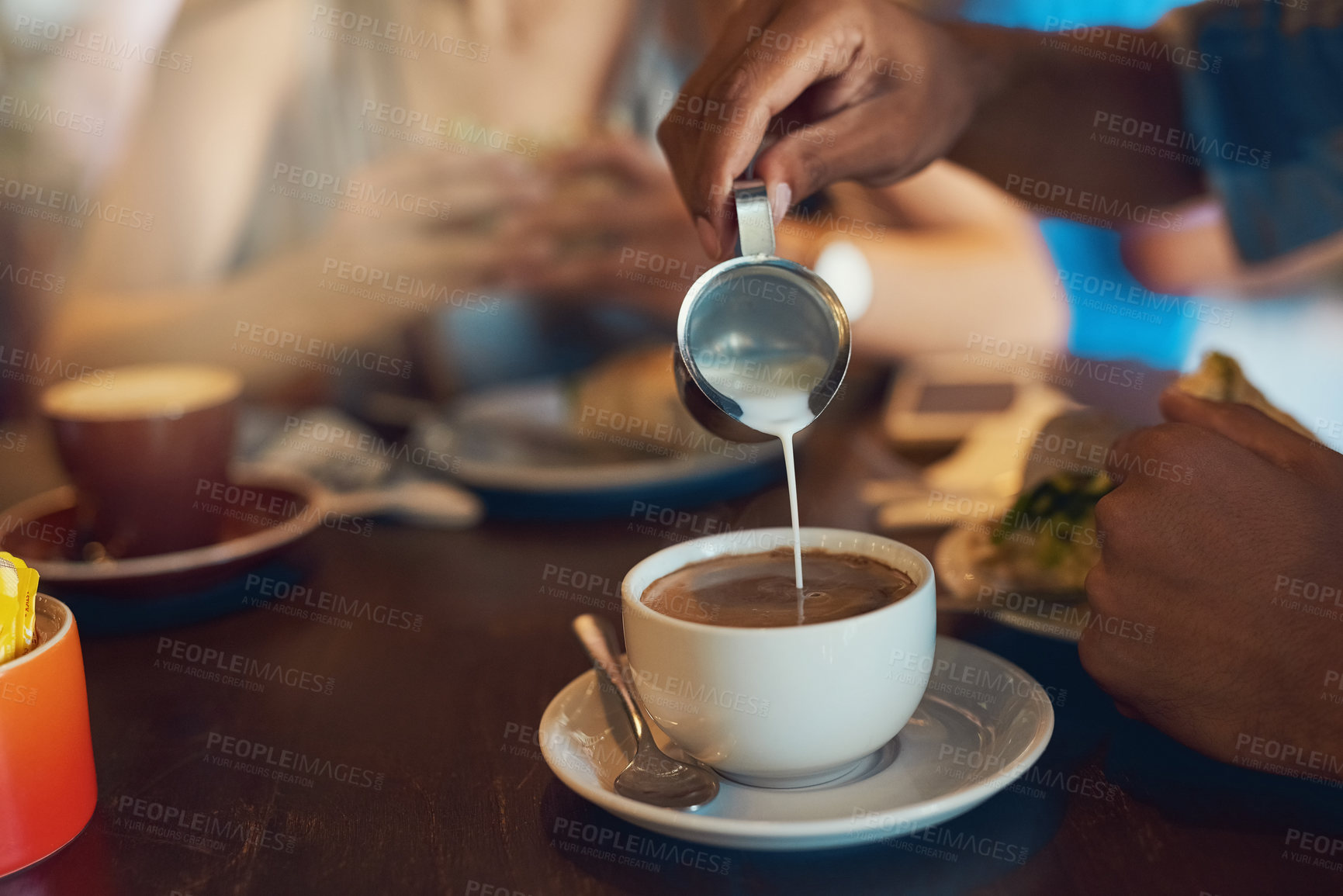 Buy stock photo Closeup shot of a person pouring milk into their cup of coffee in a cafe