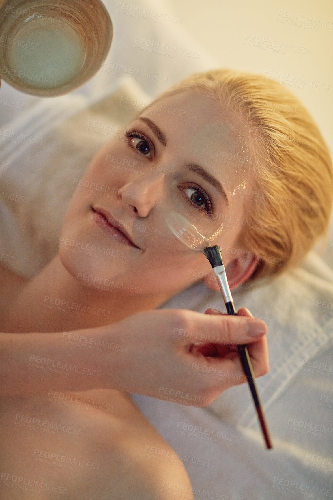 Buy stock photo Portrait of a young woman getting a facial treatment at a spa