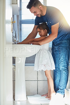Buy stock photo Shot of a father helping his little daughter wash her hands at the bathroom sink