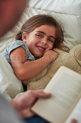 Buy stock photo Cropped shot of a little girl lying in bed while her father reads her a story