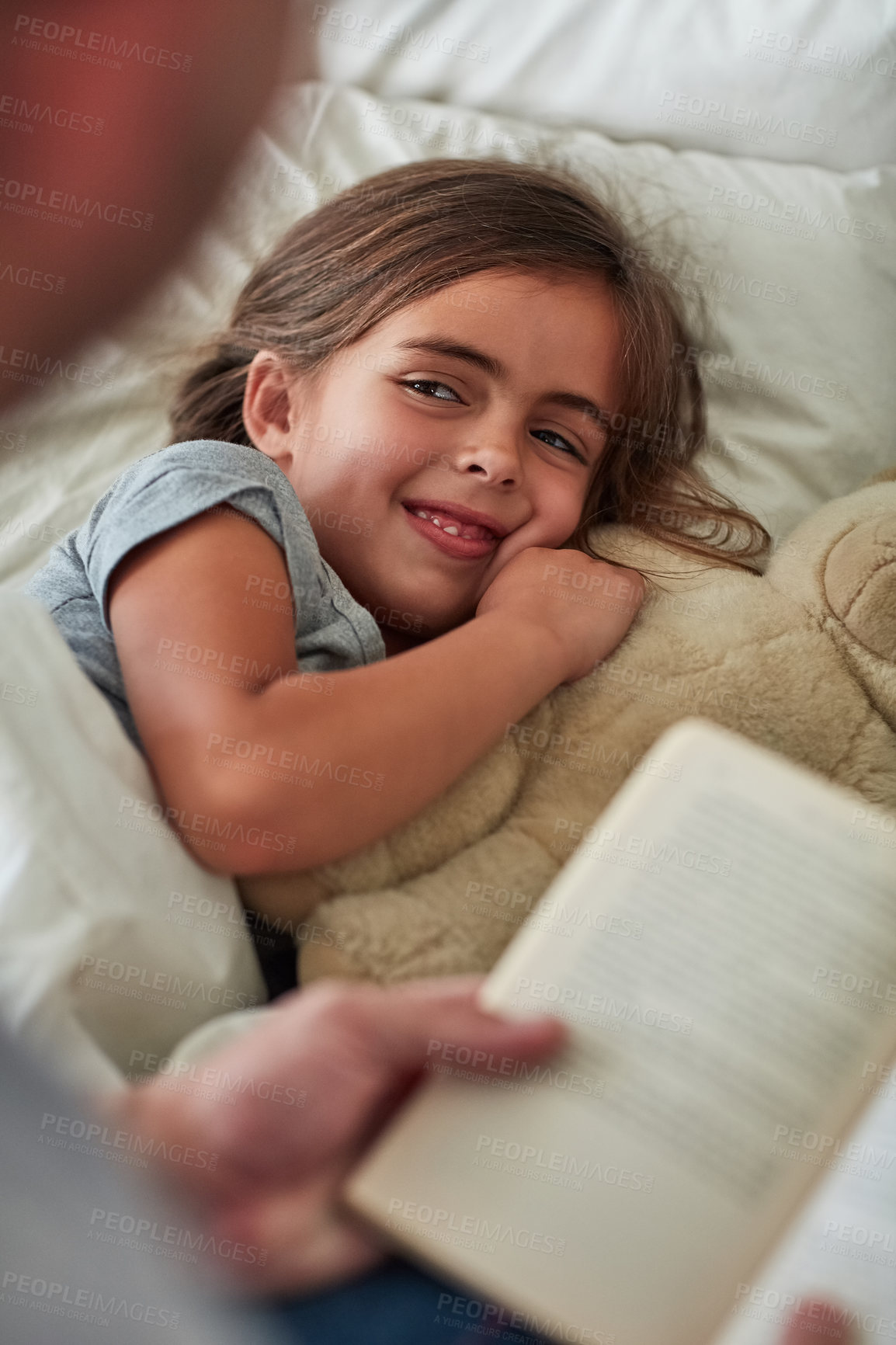 Buy stock photo Cropped shot of a little girl lying in bed while her father reads her a story
