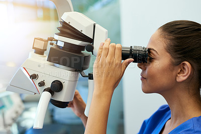 Buy stock photo Shot of a young pathologist looking at samples under a microscope