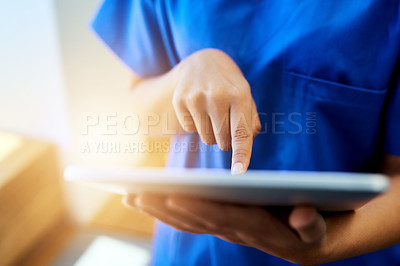 Buy stock photo Cropped shot of an unidentifiable young nurse using a tablet while standing inside a clinic