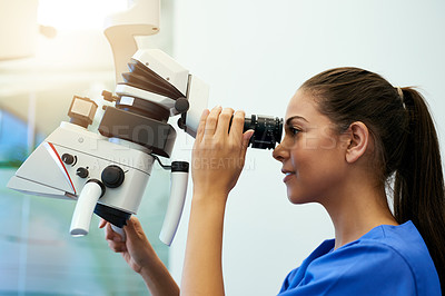 Buy stock photo Shot of a young pathologist looking at samples under a microscope