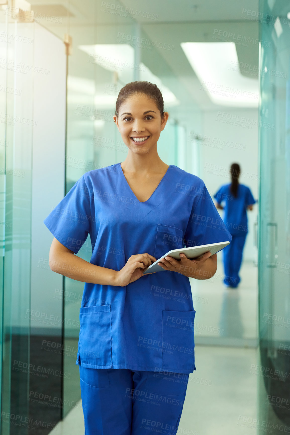 Buy stock photo Portrait of a young nurse using a tablet while standing inside a clinic