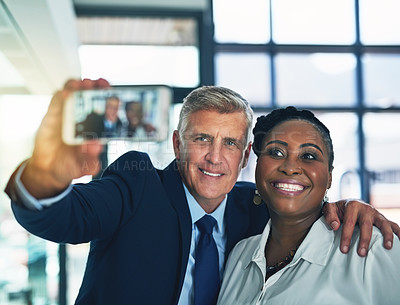 Buy stock photo Shot of two happy businesspeople posing for a selfie together in the office