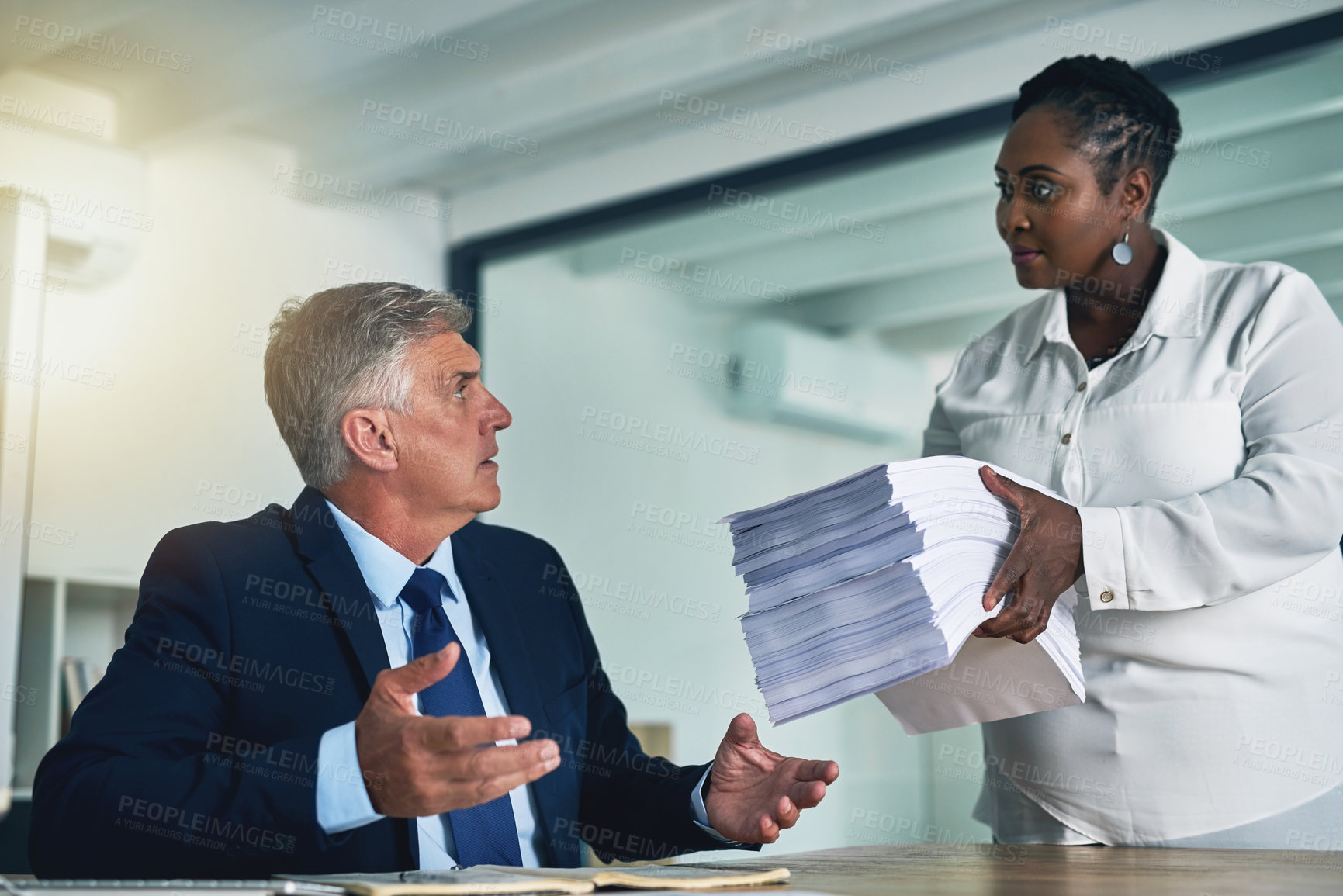 Buy stock photo Shot of a businesswoman handing a huge pile of paperwork to her overwhelmed colleague