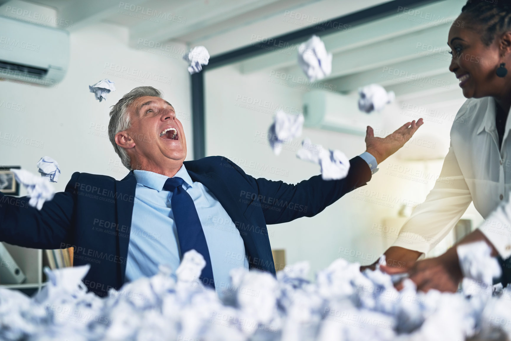 Buy stock photo Shot of two happy businesspeople throwing handfuls of crumpled paper in the air