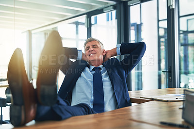 Buy stock photo Shot of a contented businessman relaxing with his feet on his desk