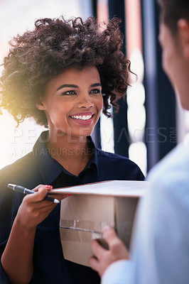 Buy stock photo Shot of a happy businesswoman signing for a package delivered by a courier in her office