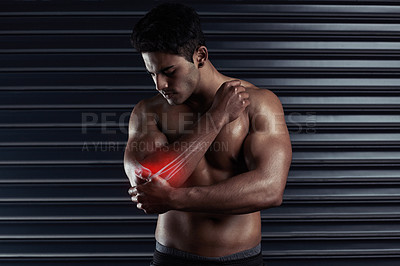 Buy stock photo Cropped shot of an athletic young man holding his elbow in pain during a workout