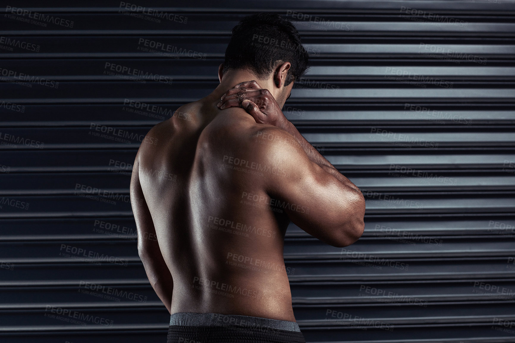 Buy stock photo Rearview shot of an athletic young man holding his neck in pain during a workout