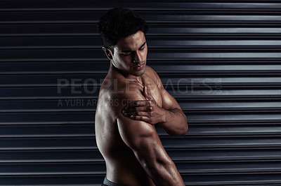 Buy stock photo Cropped shot of an athletic young man holding his shoulder in pain during a workout