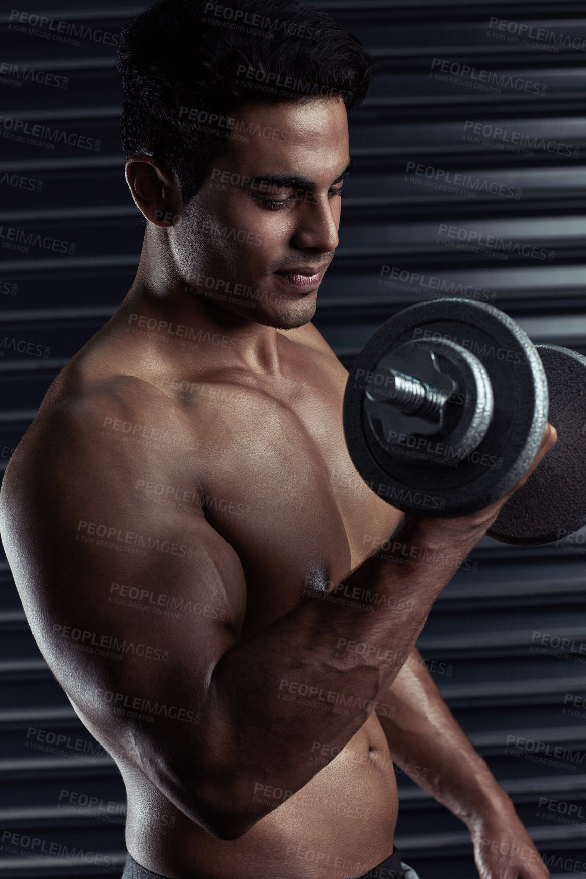 Buy stock photo Cropped shot of an athletic young man working out with a dumbbell