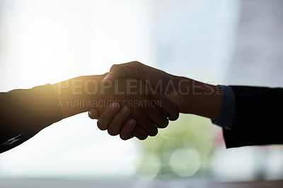 Buy stock photo Cropped shot of two silhouetted businesspeople shaking hands in the office