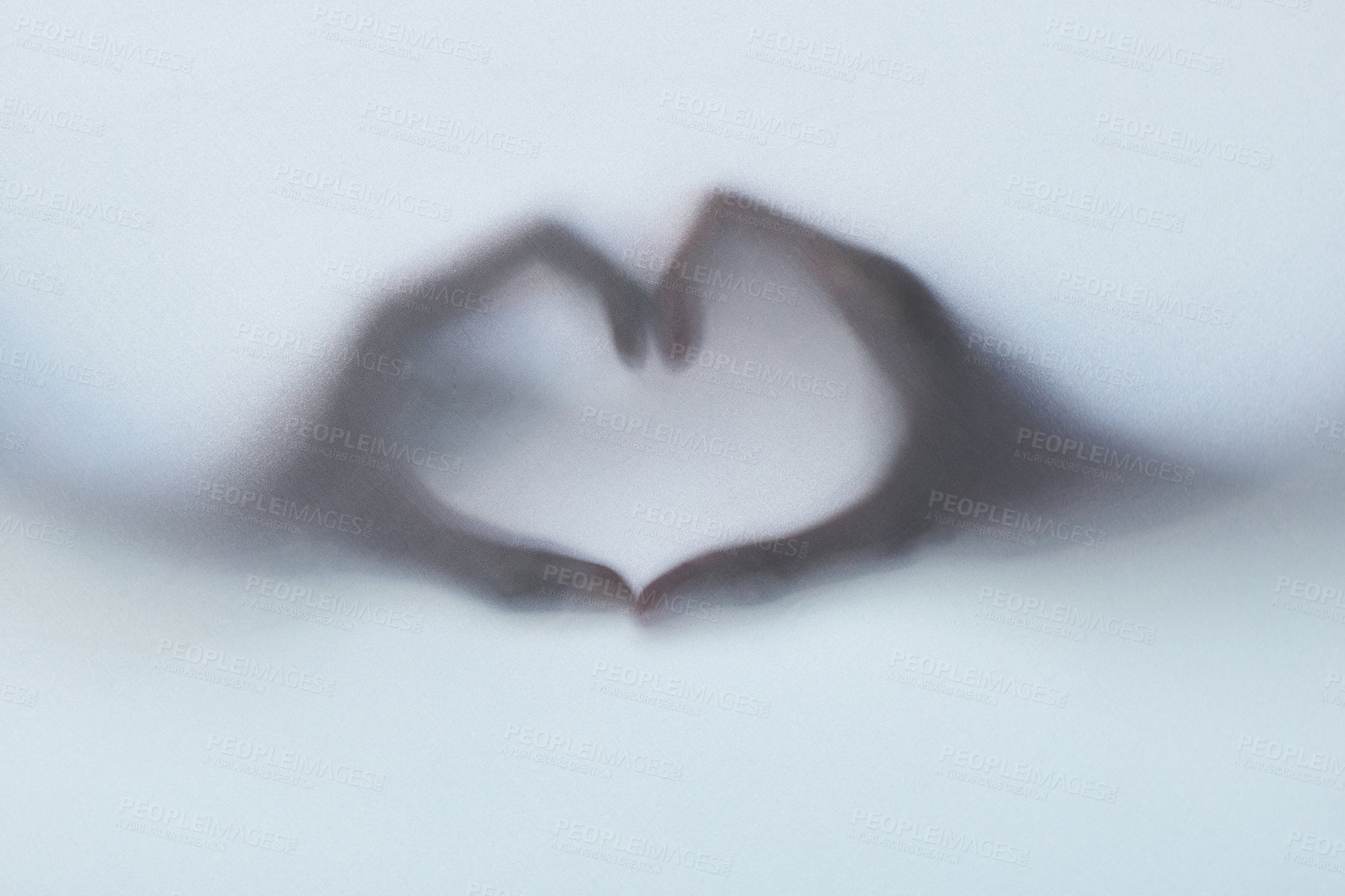 Buy stock photo Defocussed shot of two hands making a heart gesture against a plain background